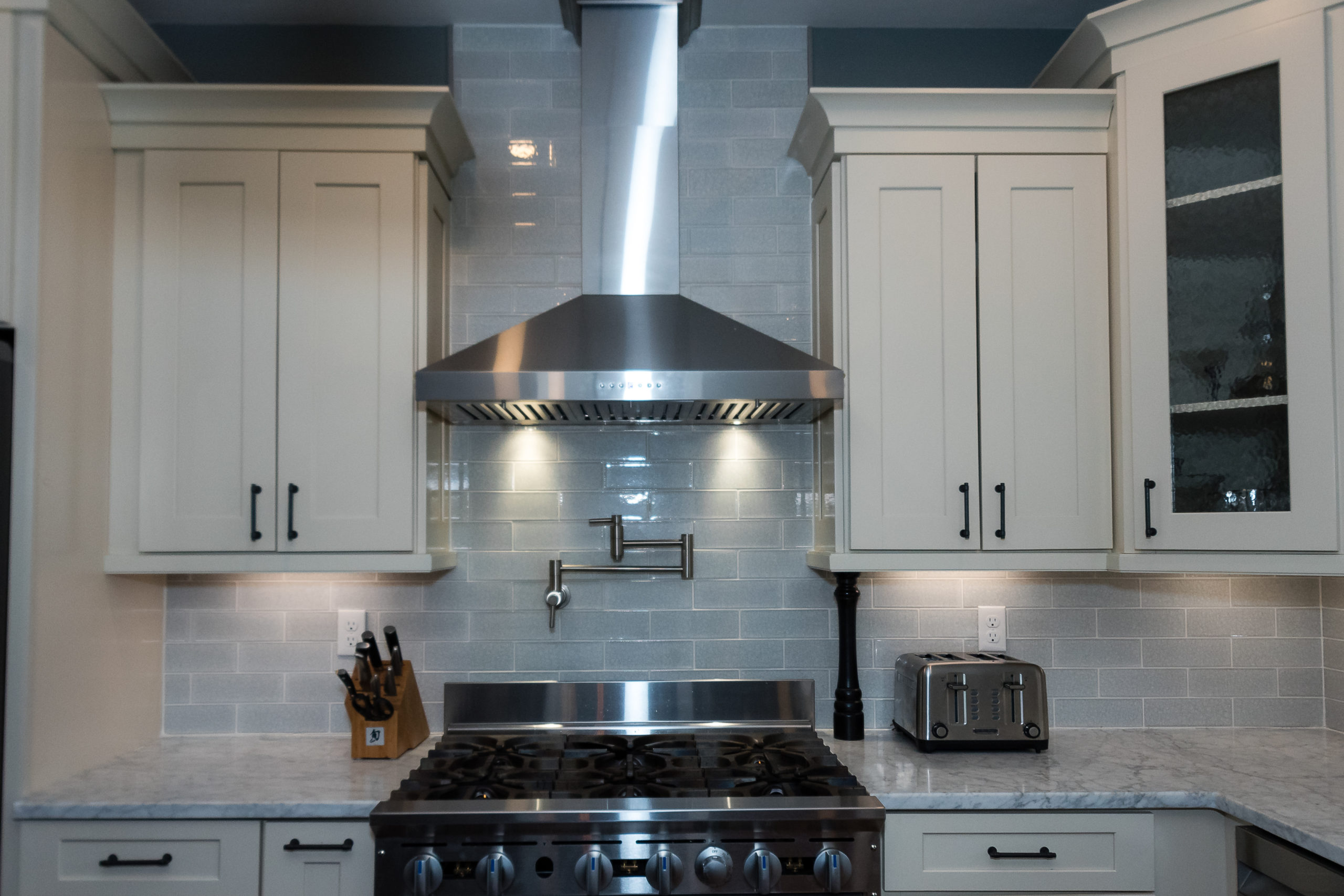 Kitchen range with stainless steel hood and white cabinets