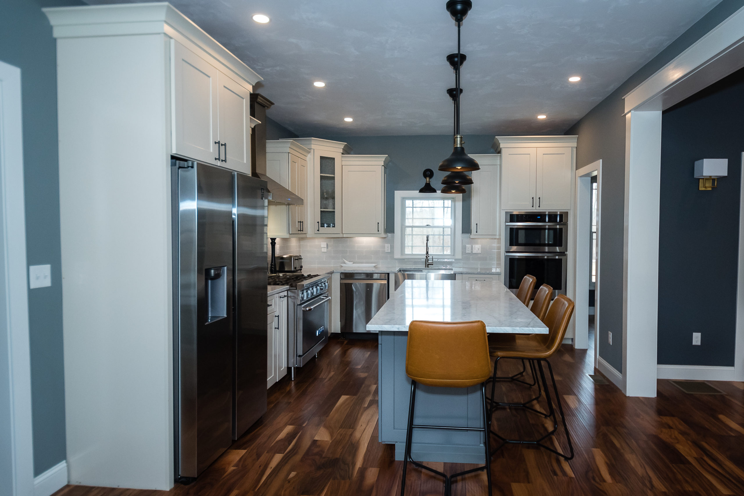 kitchen with dark hardwood floors, white cabinets and quartz countertop island