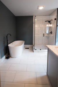 Bathroom with white porcelain tiles and custom glass shower door black fixtures